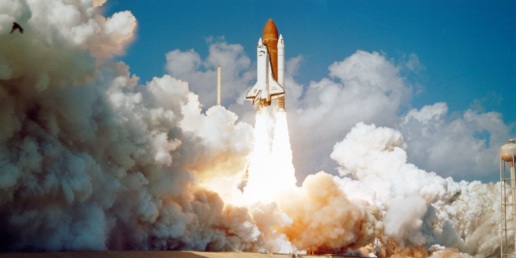 A space shuttle launching into the area with rocket boosters alight and heaps of smoke