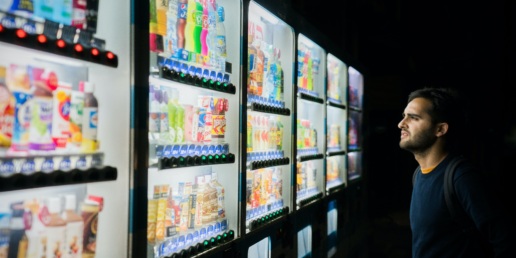 A man facing an endless wall of vending machines trying to make a decision.